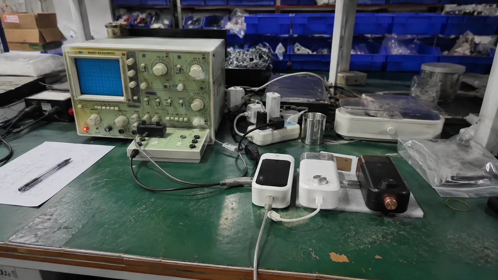 Factory testing desk with appliance samples, cables, and bench equipment
